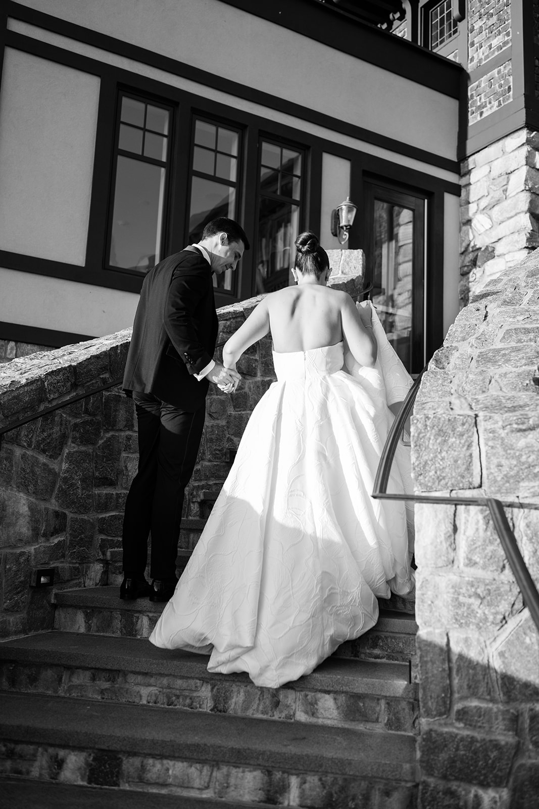 Black and white film photo of the couple walking hand-in-hand up the mansion's stone staircase.